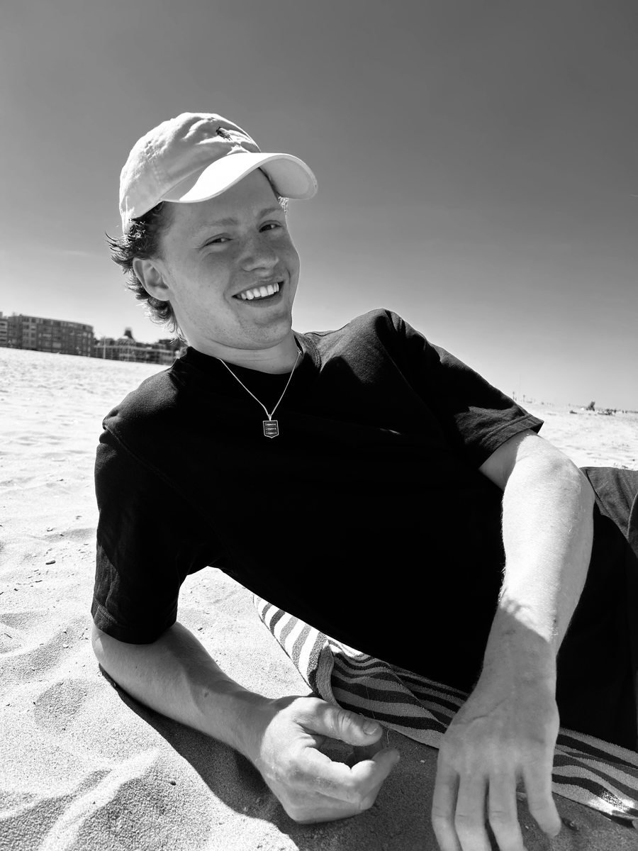 Man op het strand met een Scheveningse wapenketting, gefotografeerd in zwart-wit